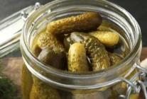 Pickled cucumbers jar grey table closeup scaled