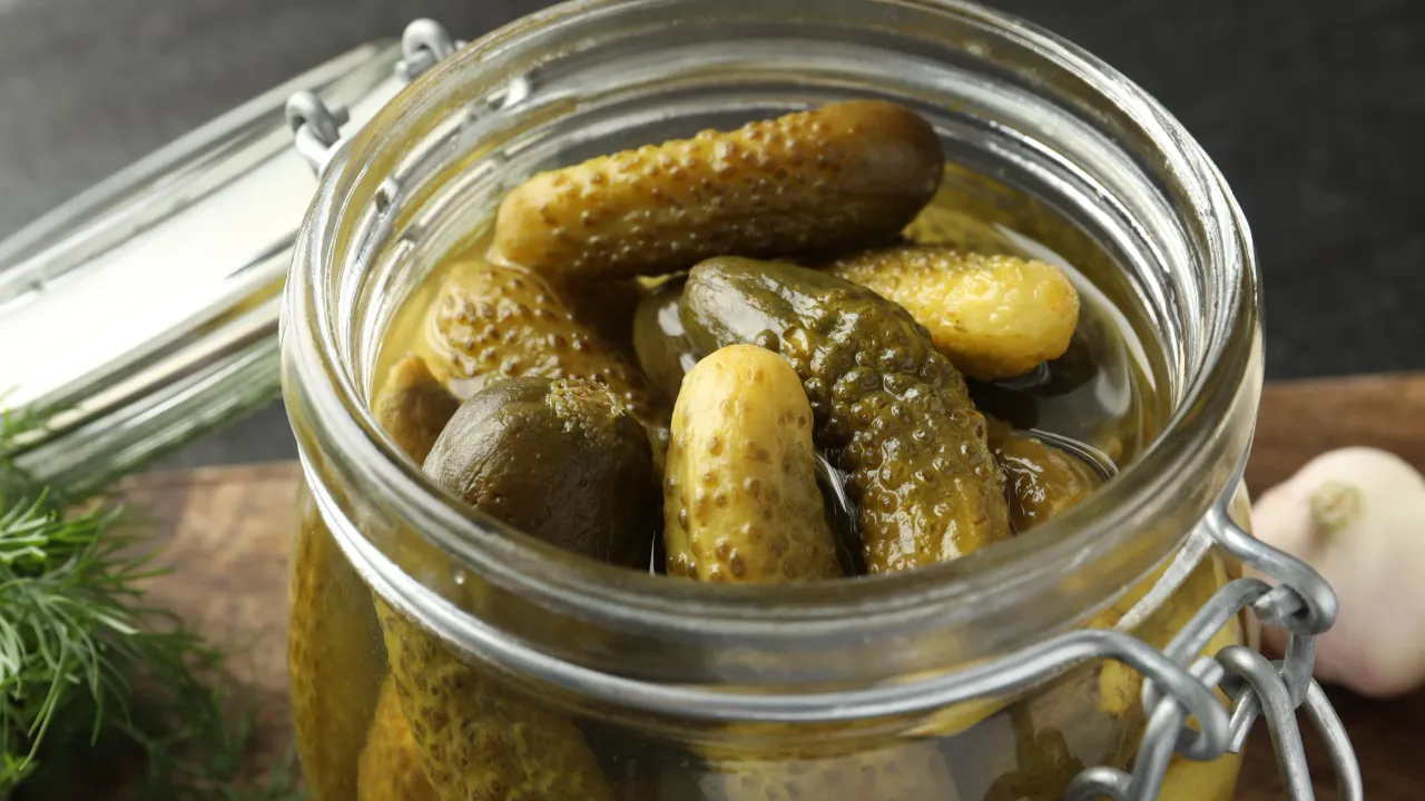 Pickled cucumbers jar grey table closeup scaled